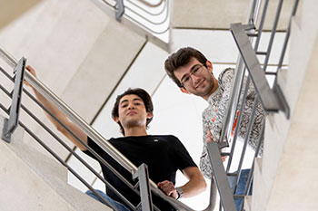 Male students standing on stairs looking over railing