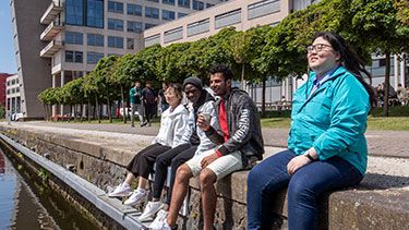 https://www.thehaguepathway.nl/wp-content/uploads/2022/11/students-sitting-on-river-edge-375x211-1.jpg.optimal.jpg