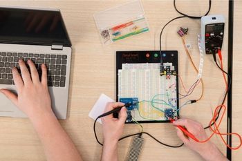 International students working in a computing lab on a circuitboard.