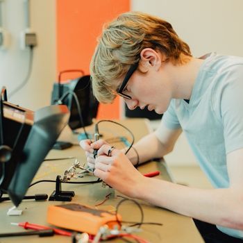 An international student at the Hague Pathway College working on an electronic circuit board.